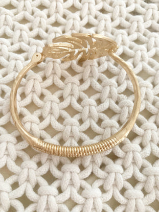 Gold leaf bangle bracelet on cream knit fabric.