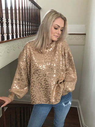 Gold metallic leopard print knit sweater; oversized fit, modeled indoors near a staircase.