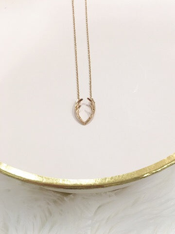 Gold antler charm necklace on delicate chain.