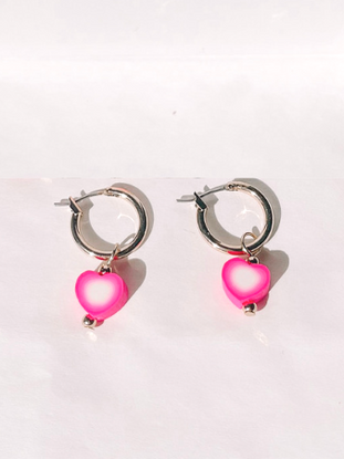 Gold hoop earrings with pink heart charms.