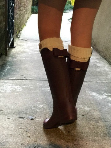 Burgundy rain boots with cream-colored socks, showcasing a bow detail on the back.