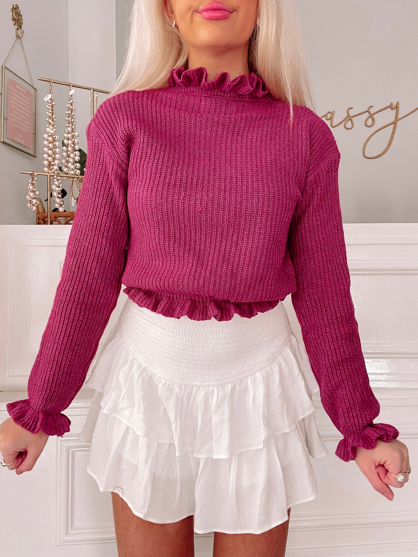 Crimson ribbed knit sweater with ruffled neckline and cuffs, styled with a white tiered skirt.