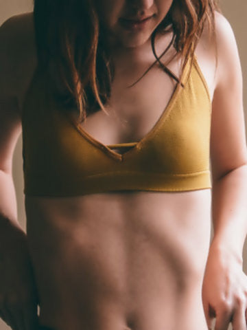 Mustard yellow bralette with a V-neckline, worn by a woman.