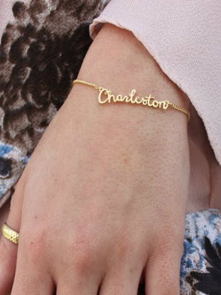 Gold Charleston nameplate bracelet on a wrist.