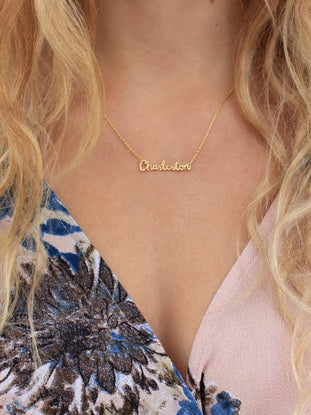 Gold cursive name necklace on model wearing floral top