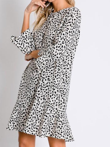 Cream-colored mini dress with a black dalmatian print, featuring a flared hem and three-quarter sleeves.