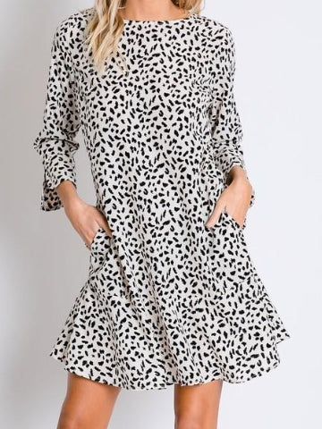 Cream-colored mini dress with a black dalmatian print, three-quarter sleeves, and side pockets.
