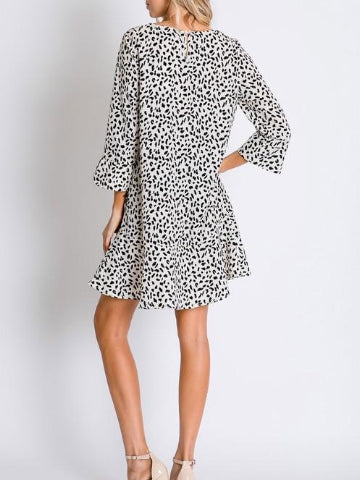 Cream-colored mini dress with a black dalmatian print, three-quarter sleeves, and a flared skirt.