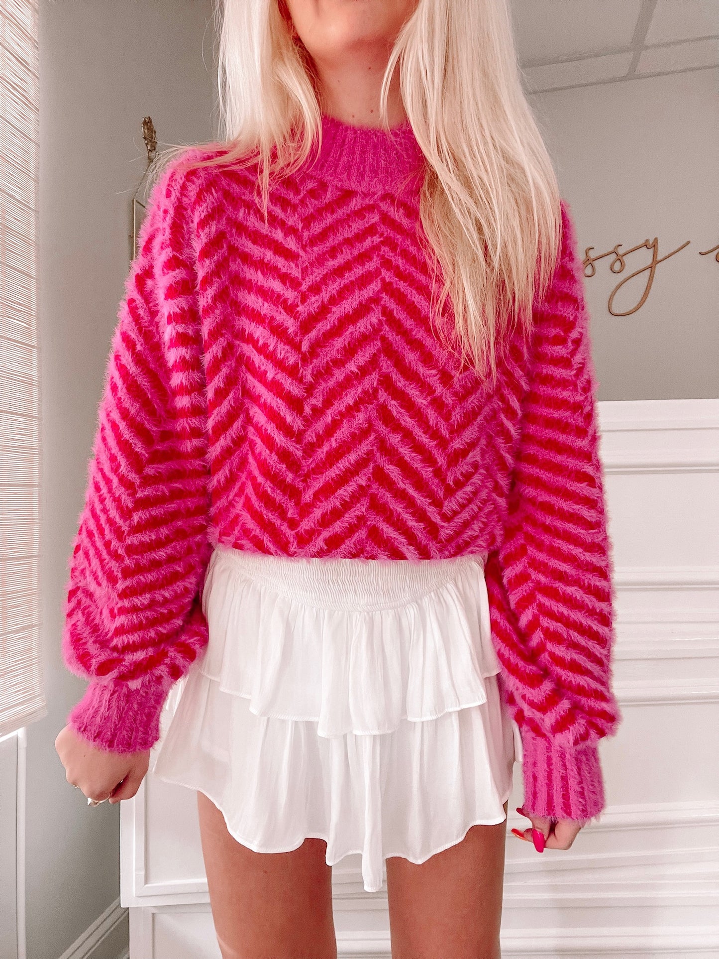 Fuzzy pink sweater with chevron pattern, styled with white ruffle skirt.