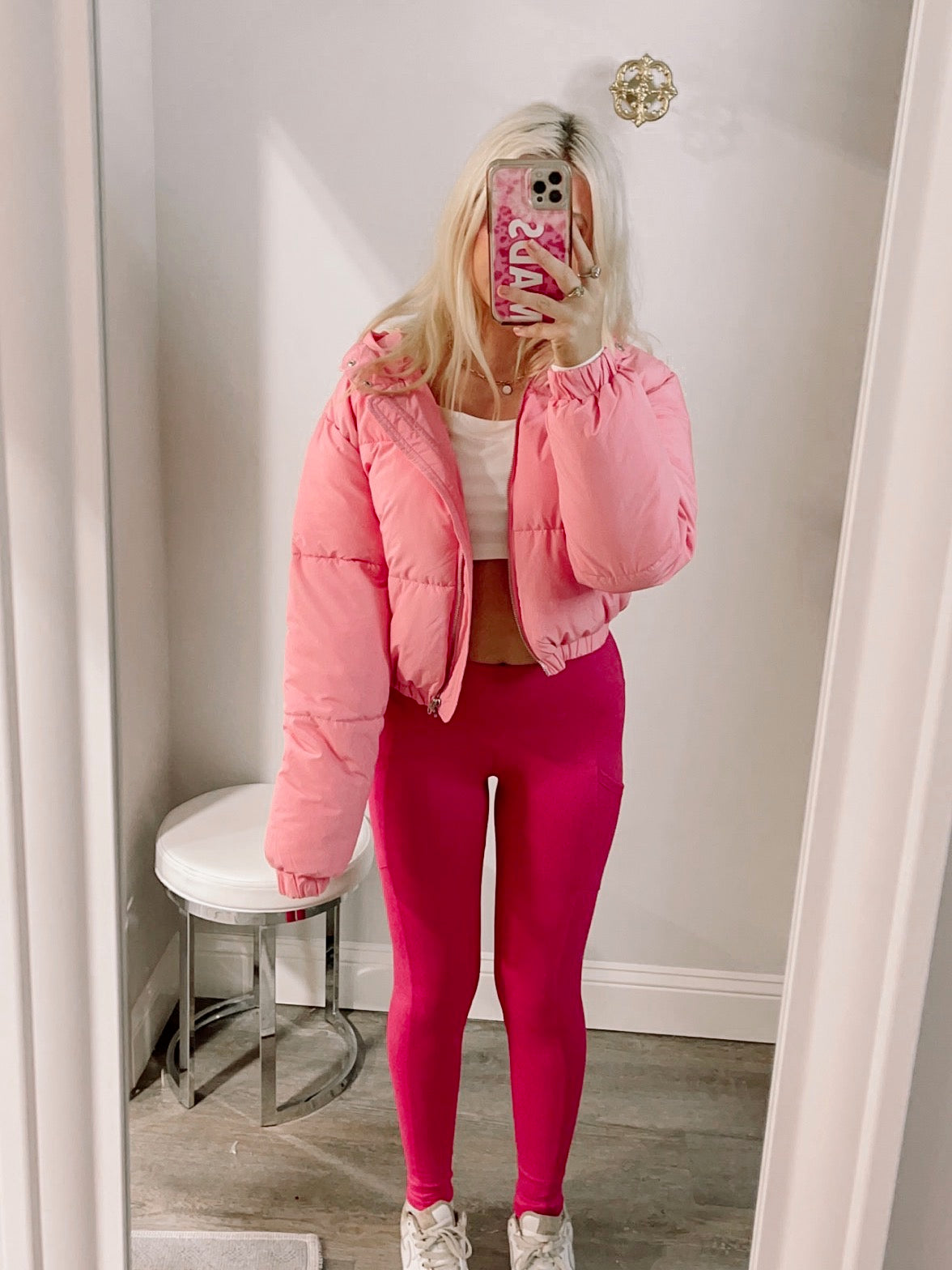 Pink puffer jacket styled with hot pink leggings in a dressing room mirror.