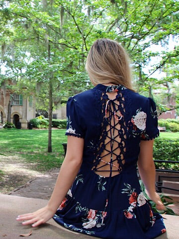 Floral navy blue dress with lace-up back detail, worn outdoors.