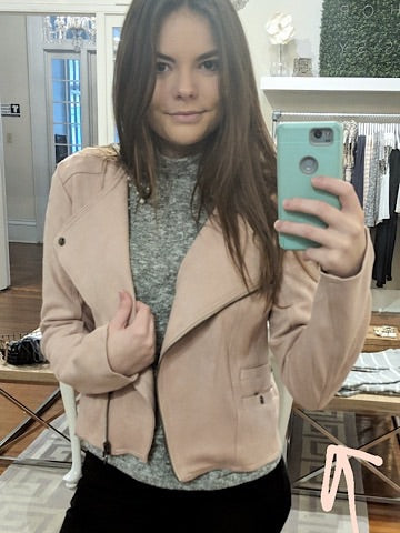 Blush pink suede moto jacket, shown on model in a boutique.