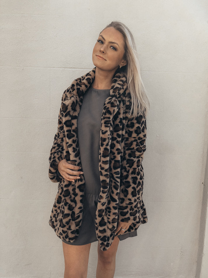 Leopard print faux fur coat styled with a gray mini dress.