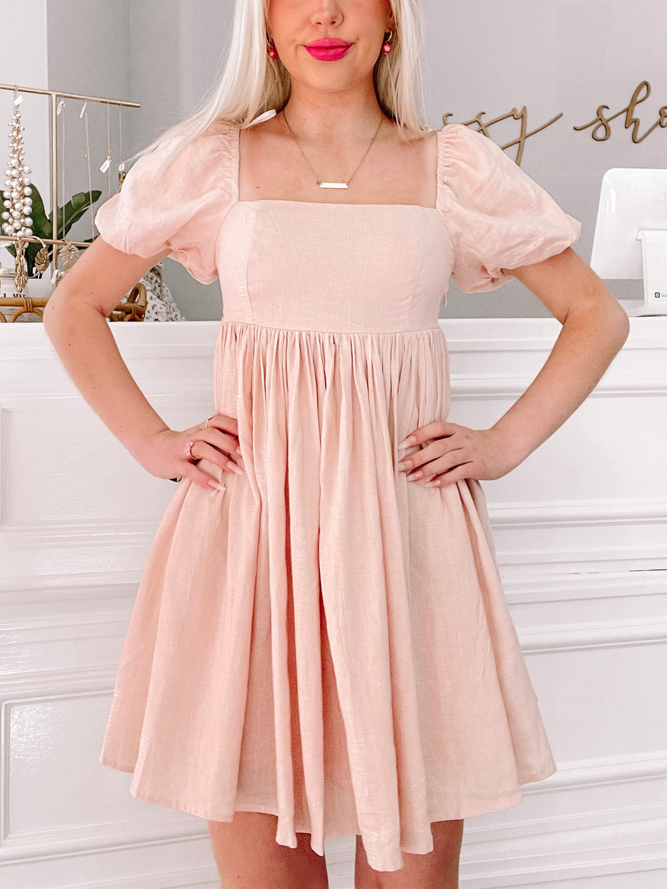 Pink mini dress with puff sleeves and square neckline, shown on a model against a white background.