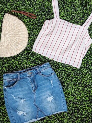 White striped tank top and distressed denim mini skirt styled on a green backdrop.