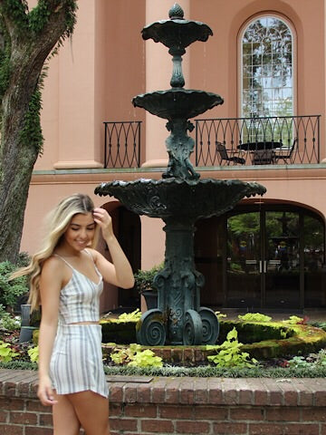 Model in striped crop top and shorts set near ornate fountain