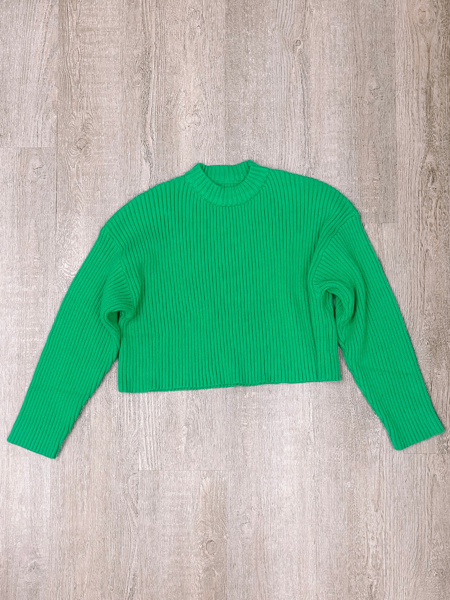 Bright green ribbed knit cropped sweater displayed on woodgrain background