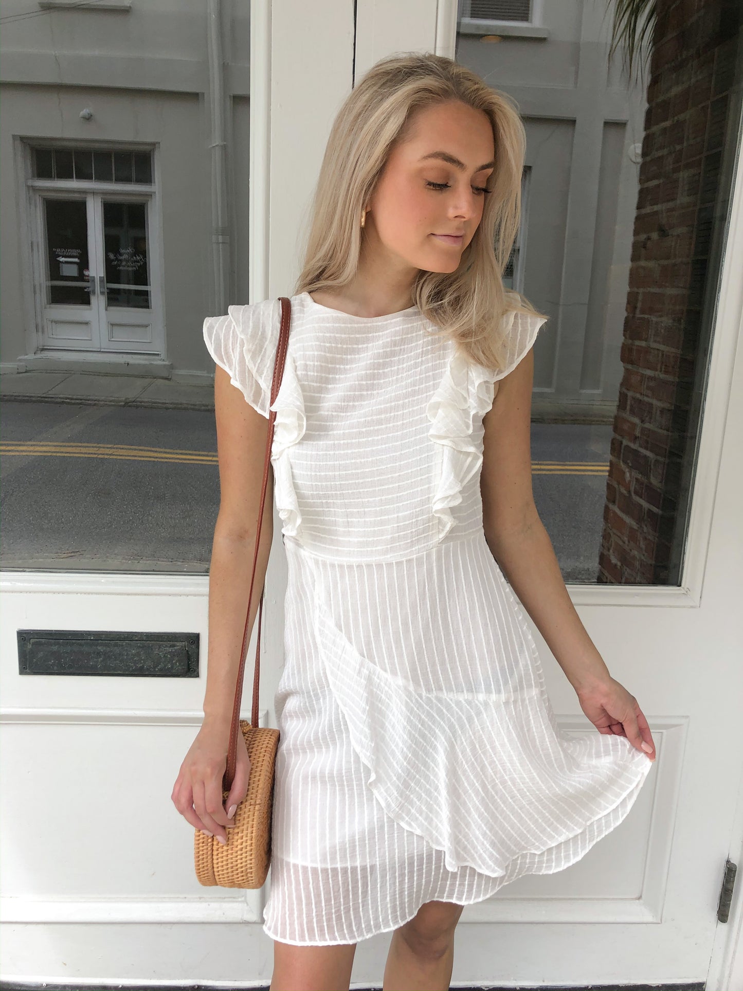 White eyelet mini dress with ruffle details, styled outdoors.