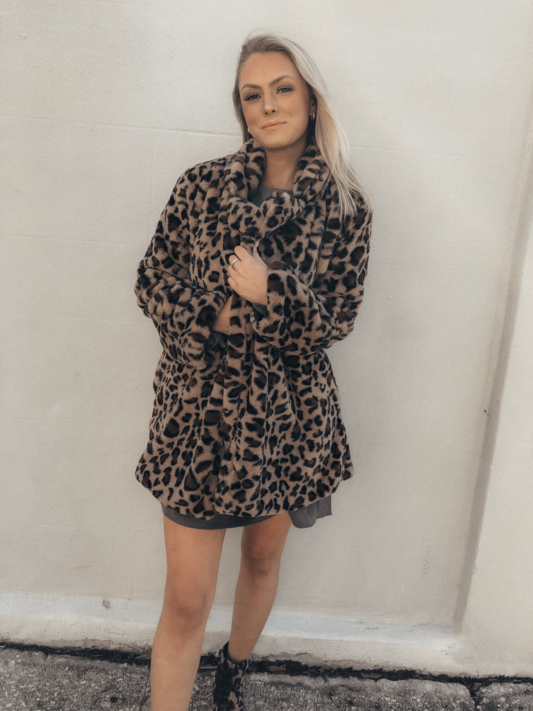 Leopard print faux fur coat styled against a white wall.