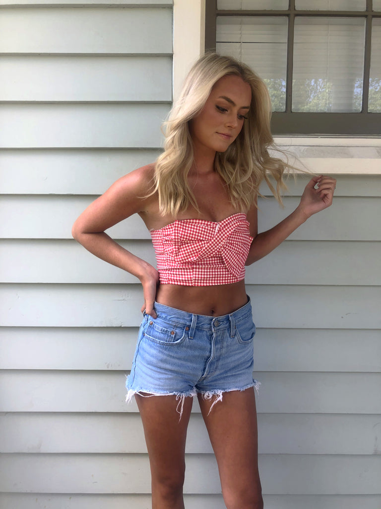 Woman in red gingham crop top and denim shorts outdoors