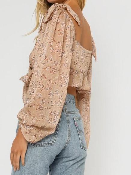 Beige floral print blouse with long sleeves and tie details, shown from the back.