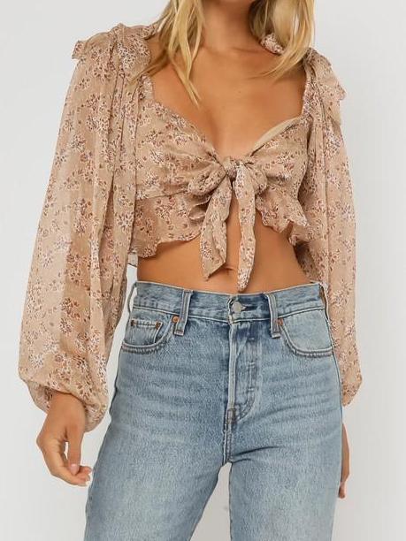 Floral print crop top with long sleeves and a front tie, modeled with light wash jeans.