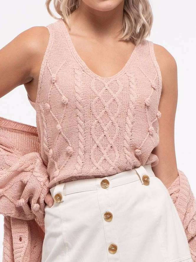 Dusty rose cable knit tank top with pom-pom accents, styled with a white button-front skirt.