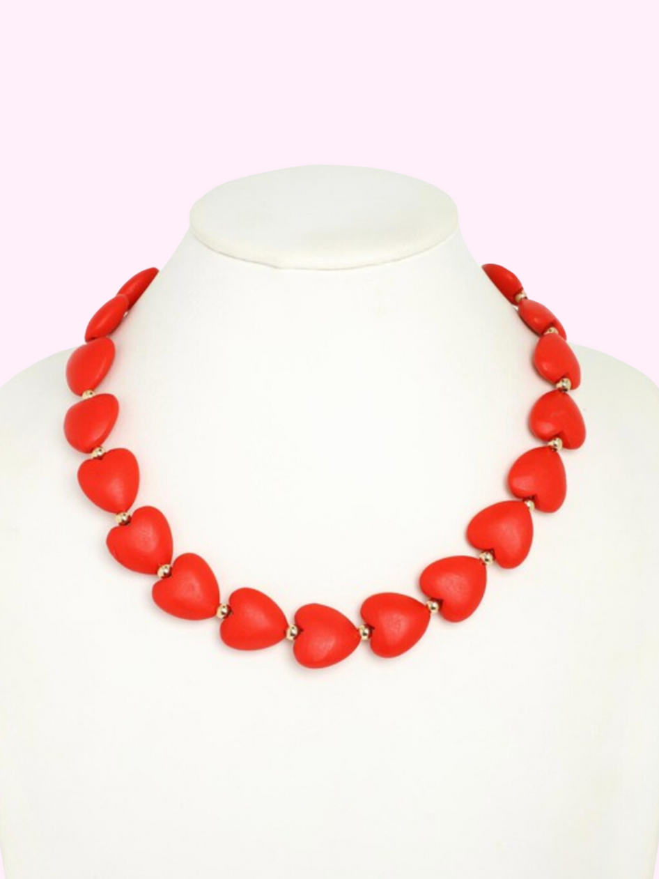 Red heart bead necklace on a mannequin, showcasing a bold statement piece.
