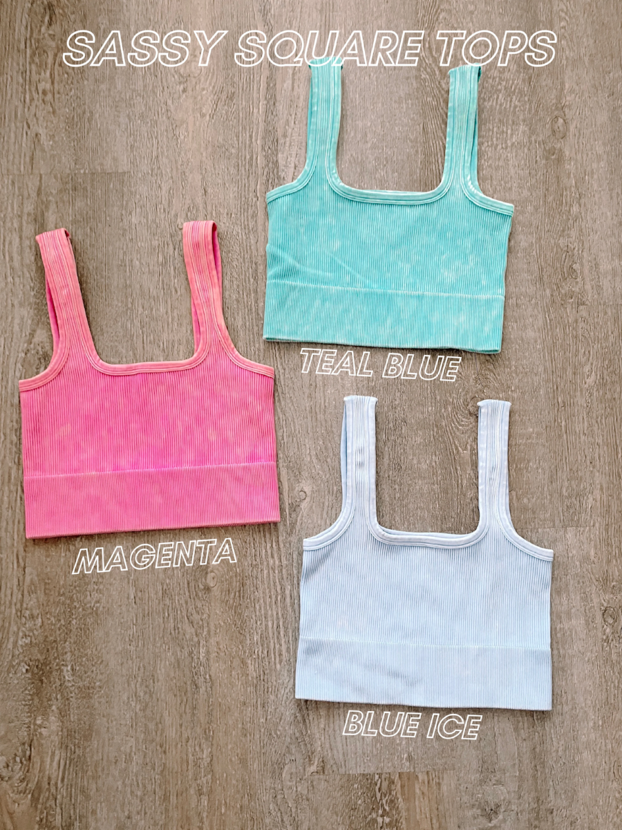 Three ribbed square-neck crop tops in magenta, teal, and light blue on wood background.

