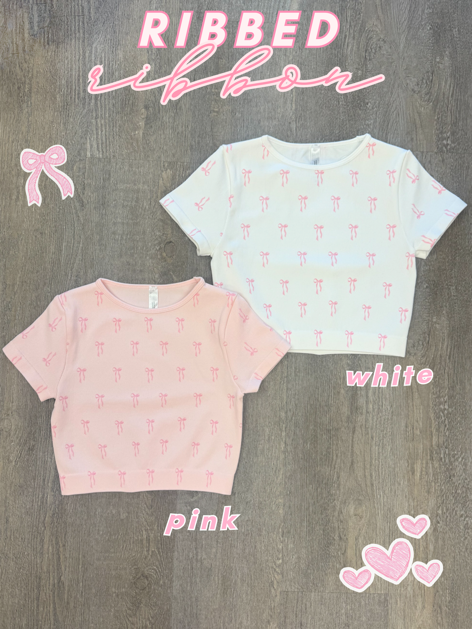 Pink & white ribbed knit crop tops with a delicate bow pattern, shown on a wood background.
