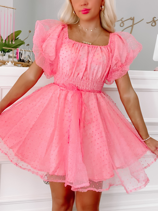 Pink Swiss dot mini dress with puff sleeves and a fitted bodice, shown on a model.
