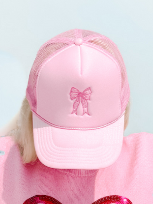 Pink satin trucker hat with embroidered bow detail, mesh back.
