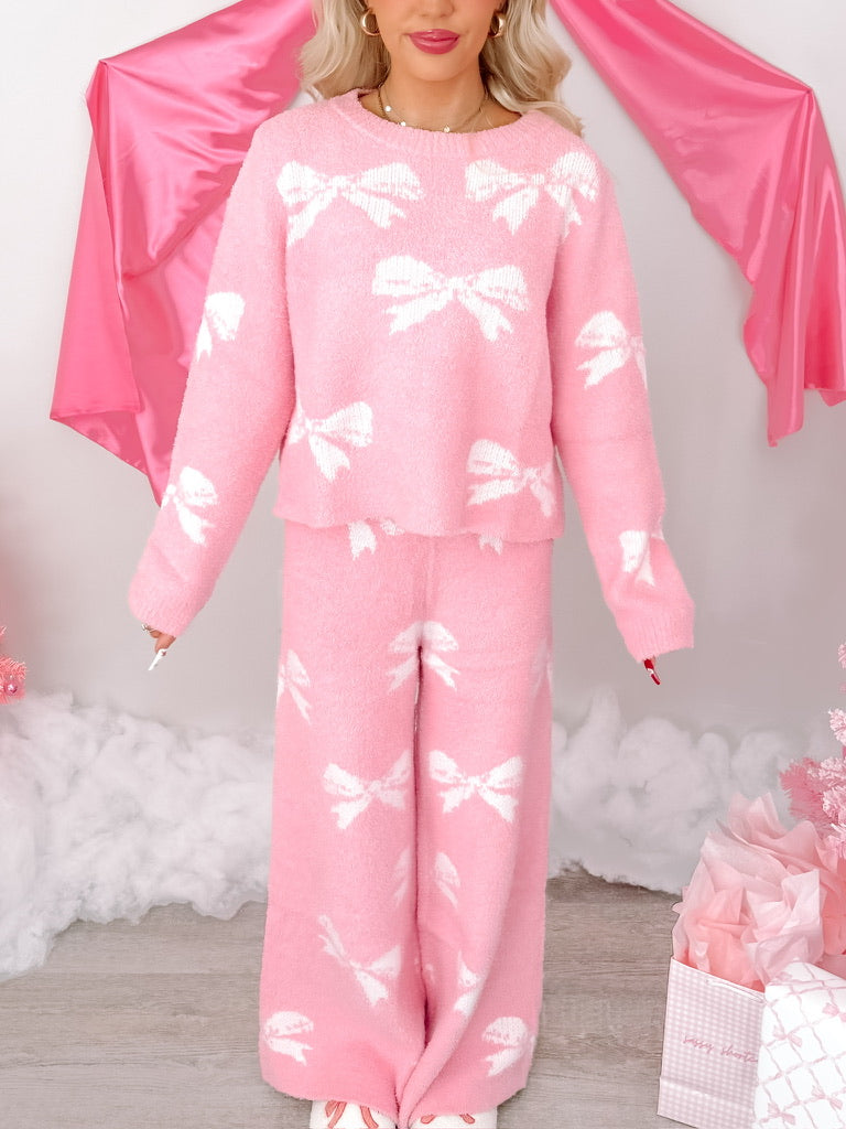 Pink fuzzy sweater and wide-leg pants set; white bow pattern.
