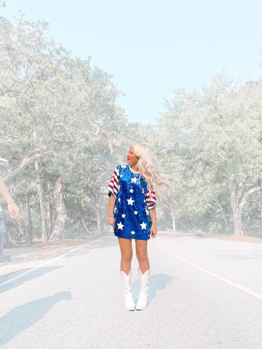 Sequined stars-and-stripes dress, worn outdoors on a road lined with trees.

