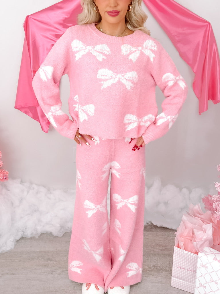 Pink fuzzy sweater and pants set; white bow pattern.
