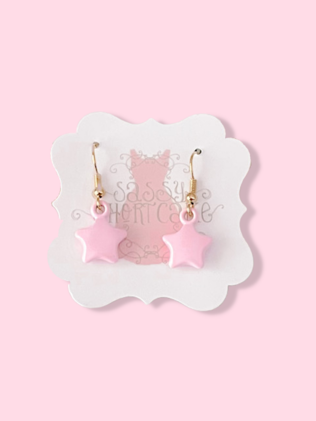 Pink star-shaped earrings with gold hooks, displayed on a product card against a pink backdrop.
