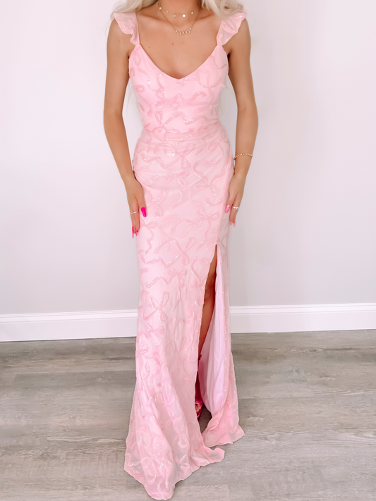 Pink Bowquette ruffle maxi dress with sequined bow detail and leg slit.
