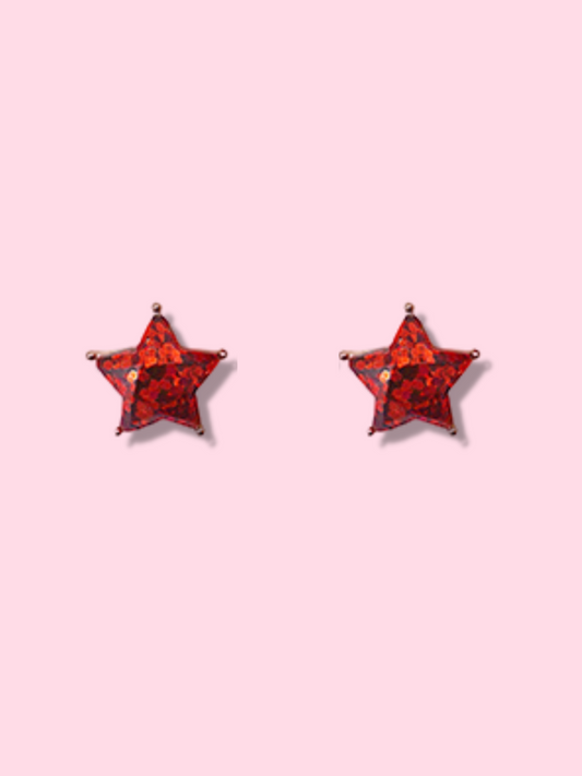Red glitter star-shaped stud earrings on a pink background.