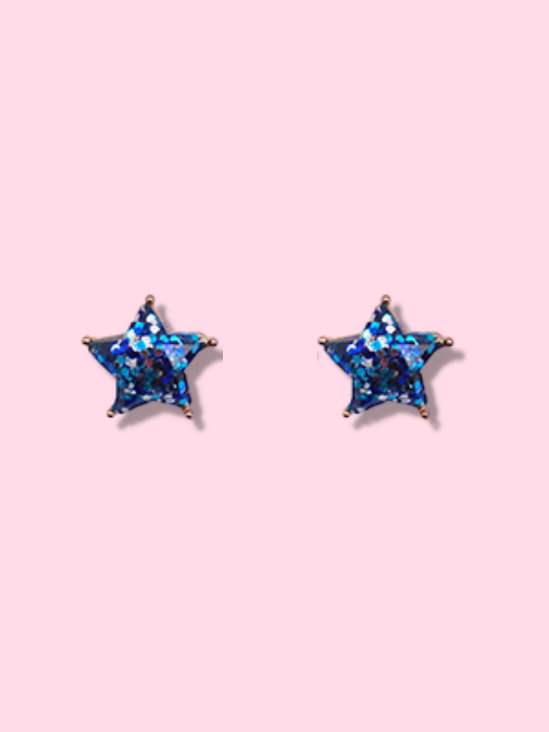 Sparkling blue glitter star stud earrings against a pink background.
