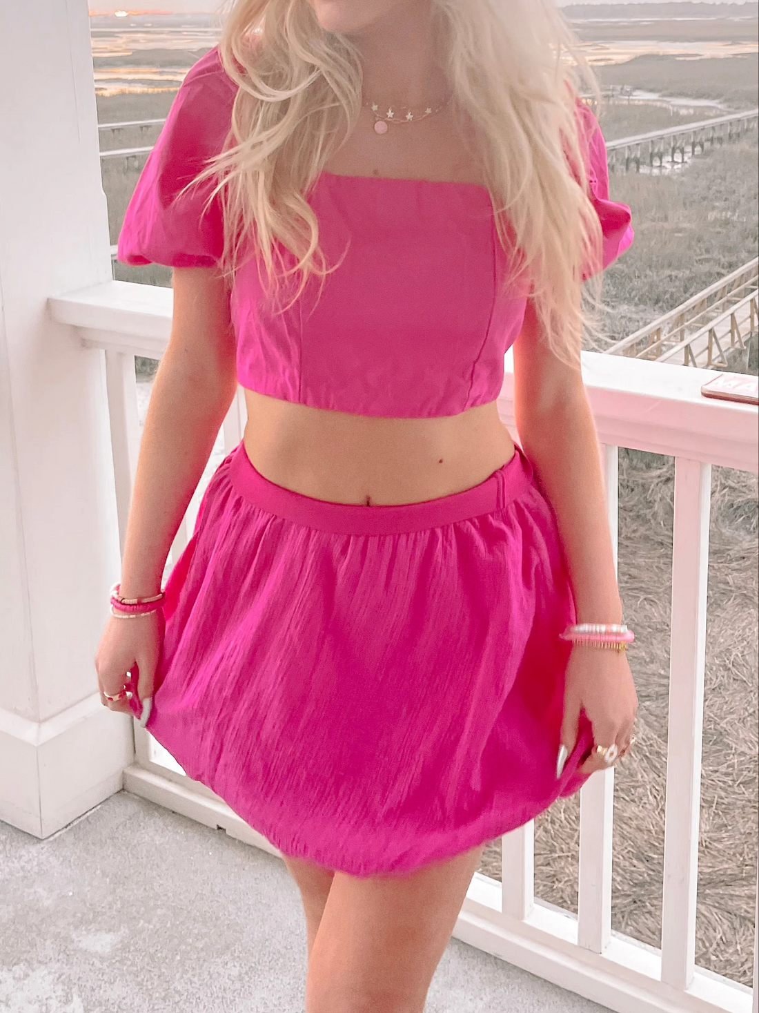 Hot pink mini skirt on a model, outdoors on a porch.
