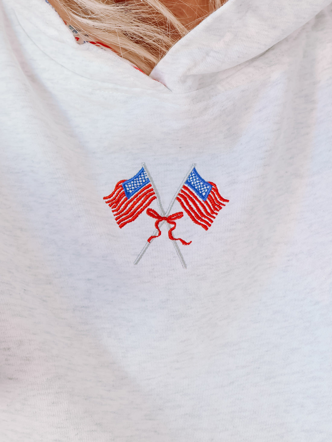 Close-up of embroidered flag patch on patriotic grey hoodie.