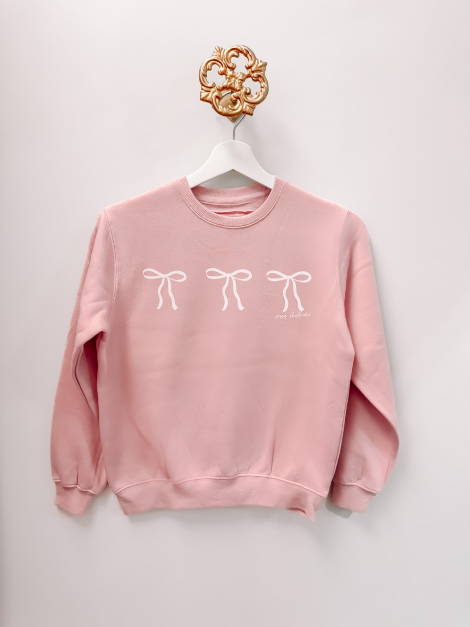 Blushing Bow Kids Crewneck blush pink sweatshirt with three white bow accents; Sassy Shortcake design.
