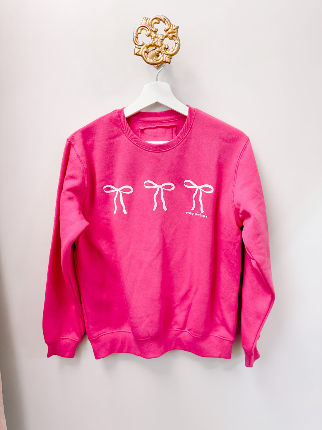 Berry pink kids' crewneck sweatshirt with three white bows.
