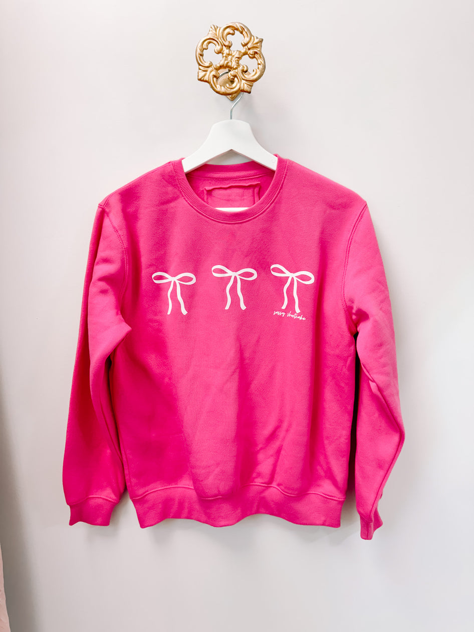 Berry pink kids' crewneck sweatshirt with three white bows.

