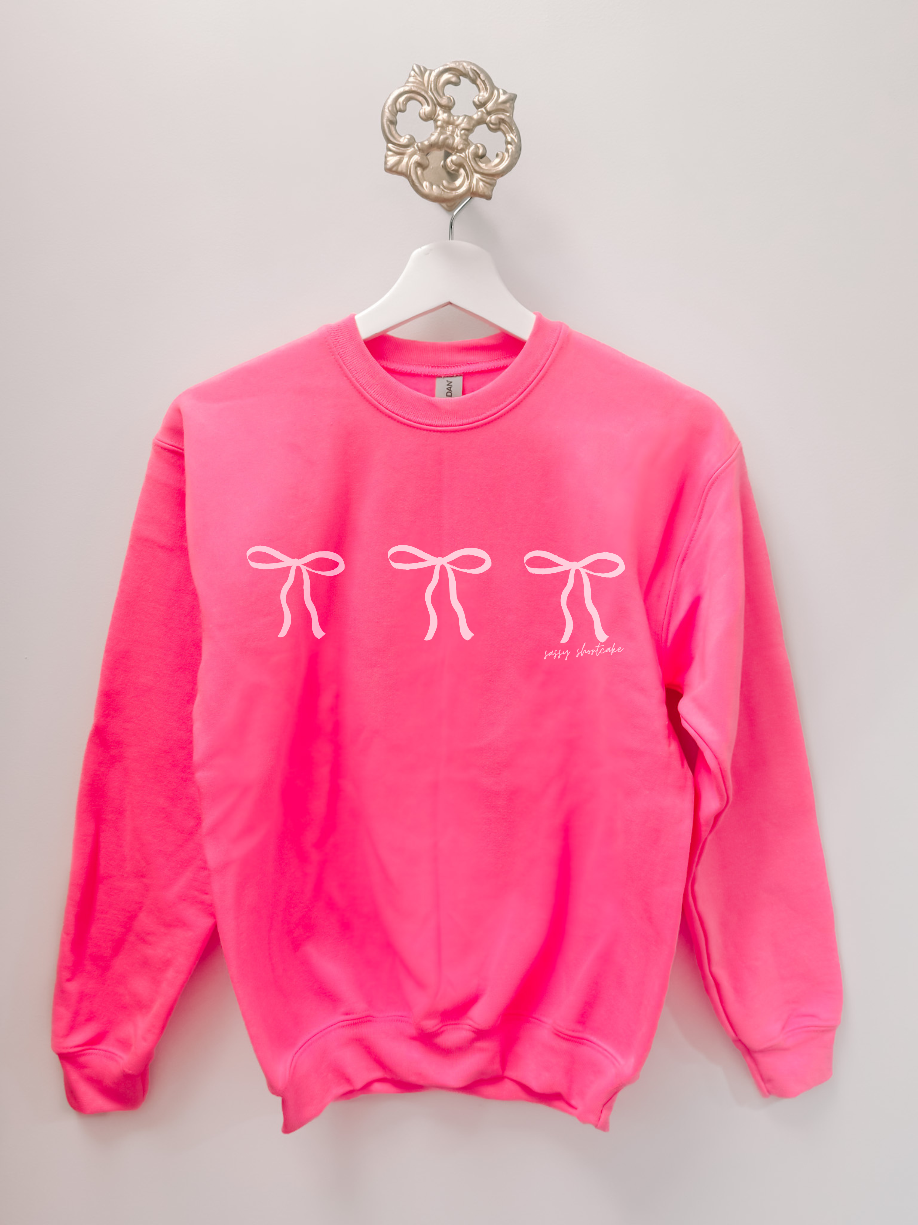 Hot pink kids' Blushing Bow crewneck sweatshirt with three white bows and 