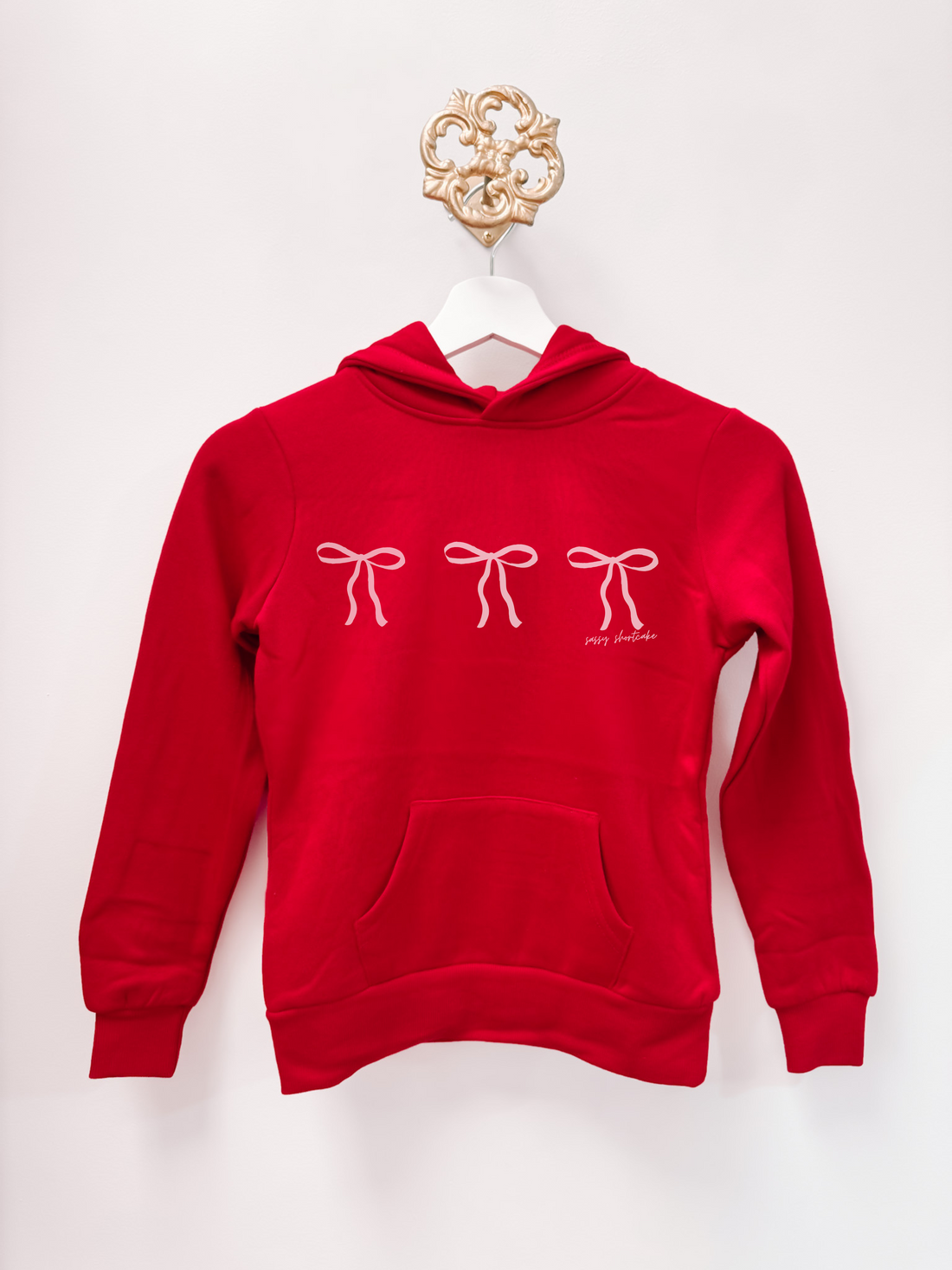 Sassy Shortcake Blushing Bow Kids Hoodie: Red kids hoodie with three pink bows.

