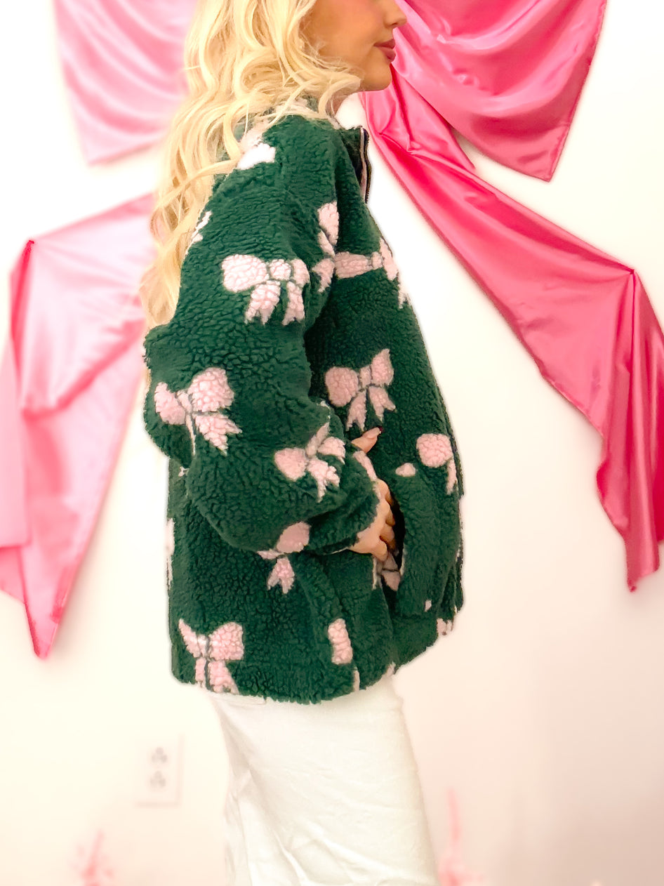 Hunter green sherpa material jacket with pink bows, quarter zip, and pockets for essentials, modeled on figure. Bundled in Bows from Sassy Shortcake