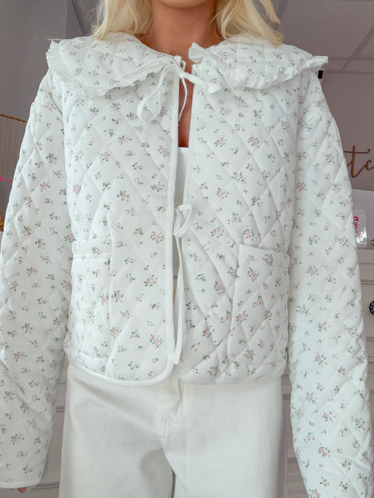 Cate Floral Jacket from Sassy Shortcake - Person wearing a white floral quilted jacket indoors.