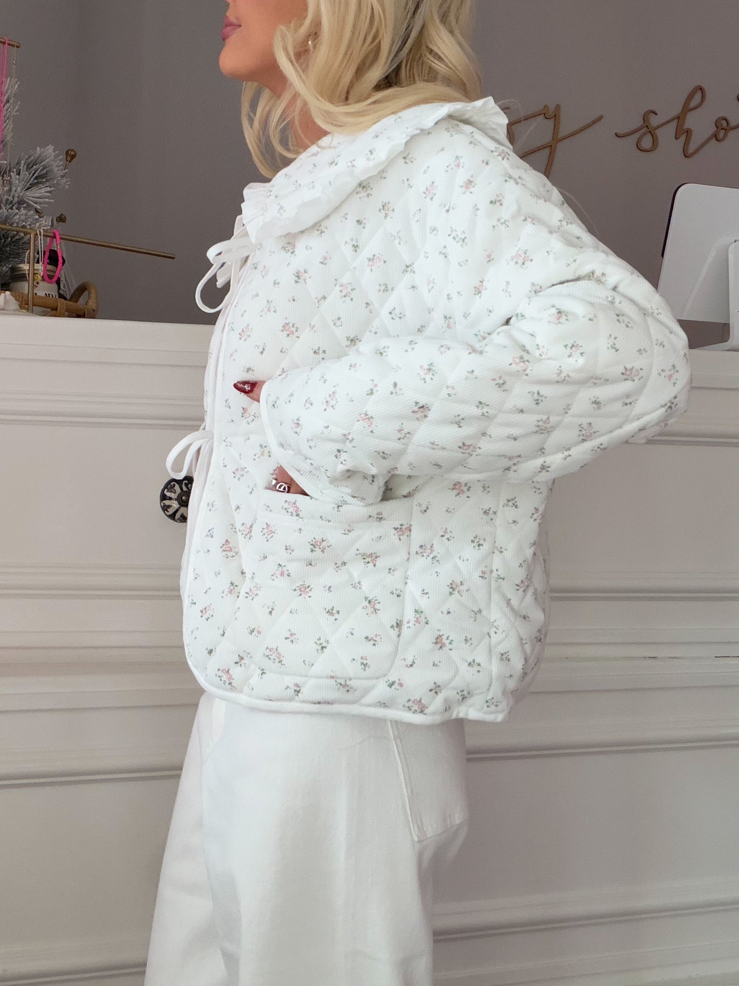 Cate Floral Jacket from Sassy Shortcake - White floral-patterned quilted jacket worn by a person indoors.