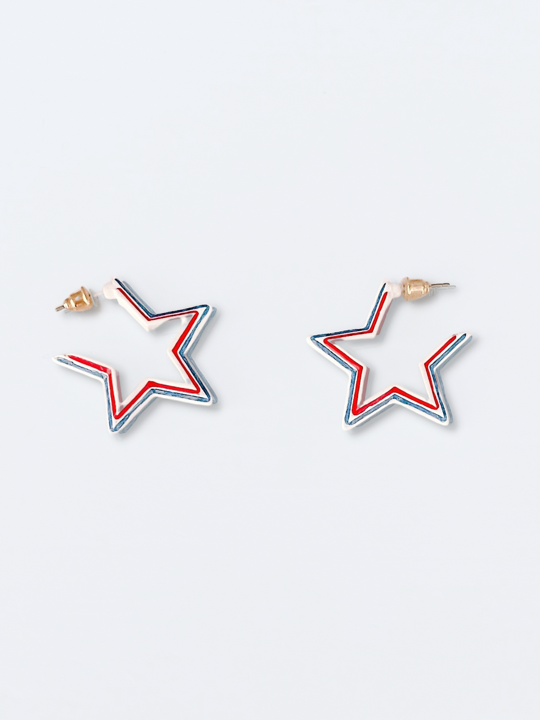 Red, white, and blue star-shaped hoop earrings against a light background.
